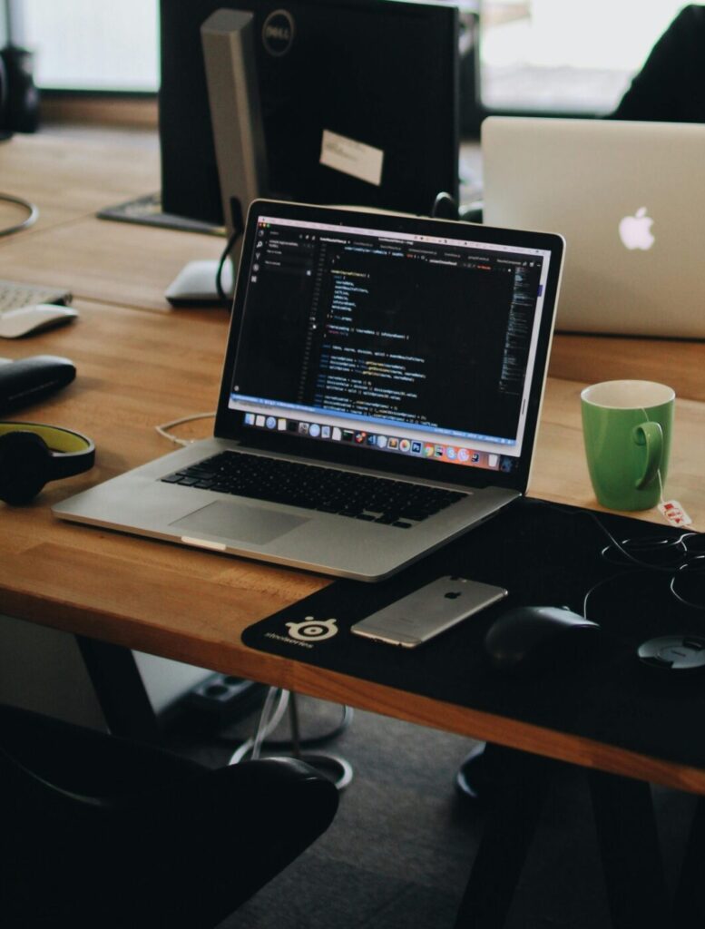 A web developer working on code in a modern office setting with multiple devices.